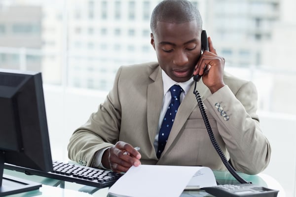 Entrepreneur making a phone call while reading a document in his office