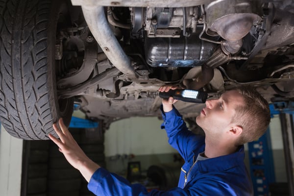 Male mechanic examining car using flashlight-1