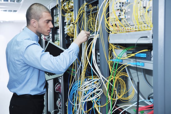 young engeneer business man with thin modern aluminium laptop in network server room